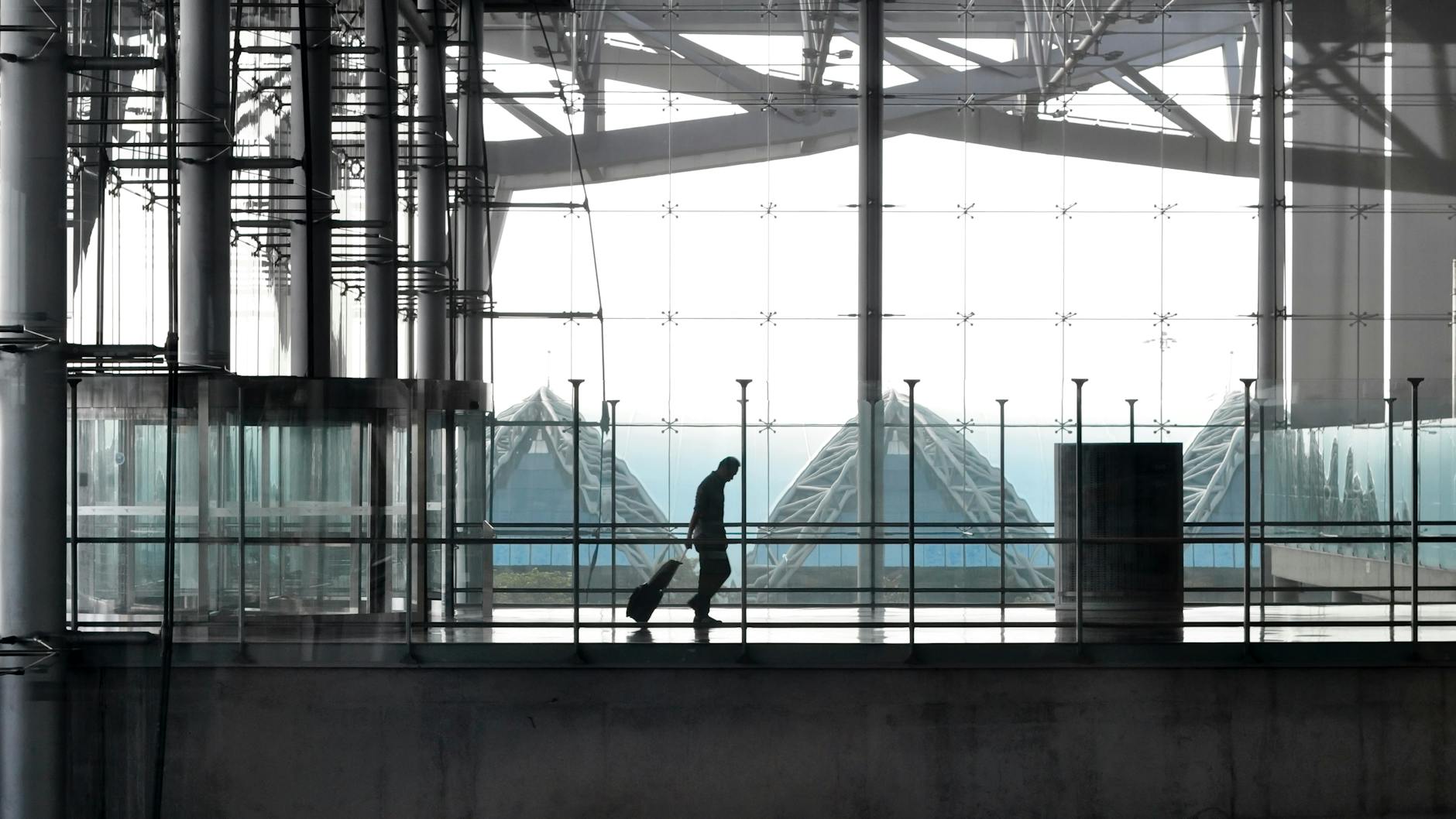 traveler in glass airport terminal walkway